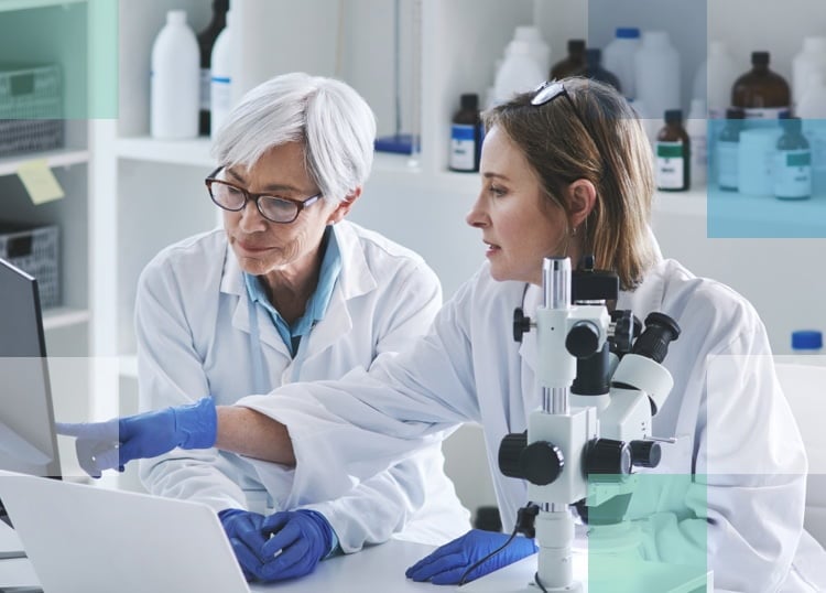 Two female eye care professionals doing research on a computer with a microscope.
